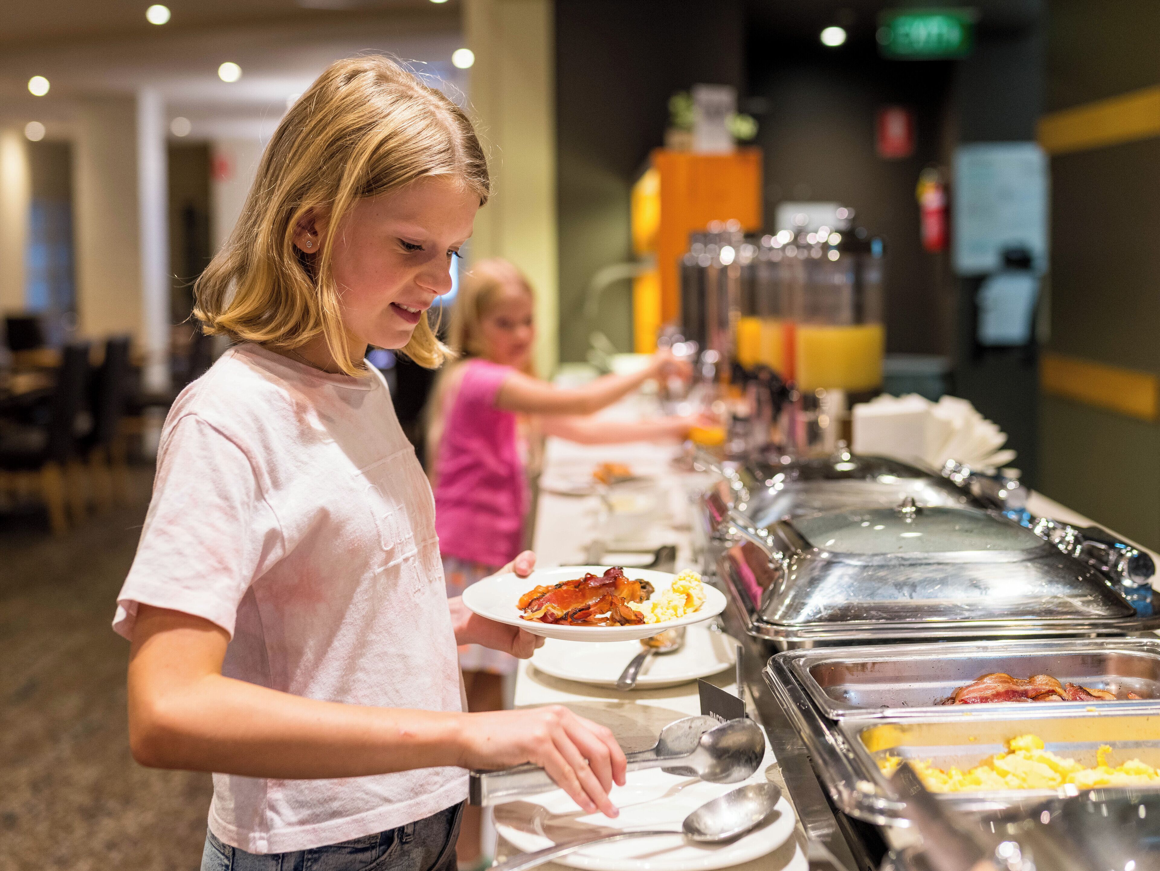 A buffet area with various food options and a person serving themselves.
