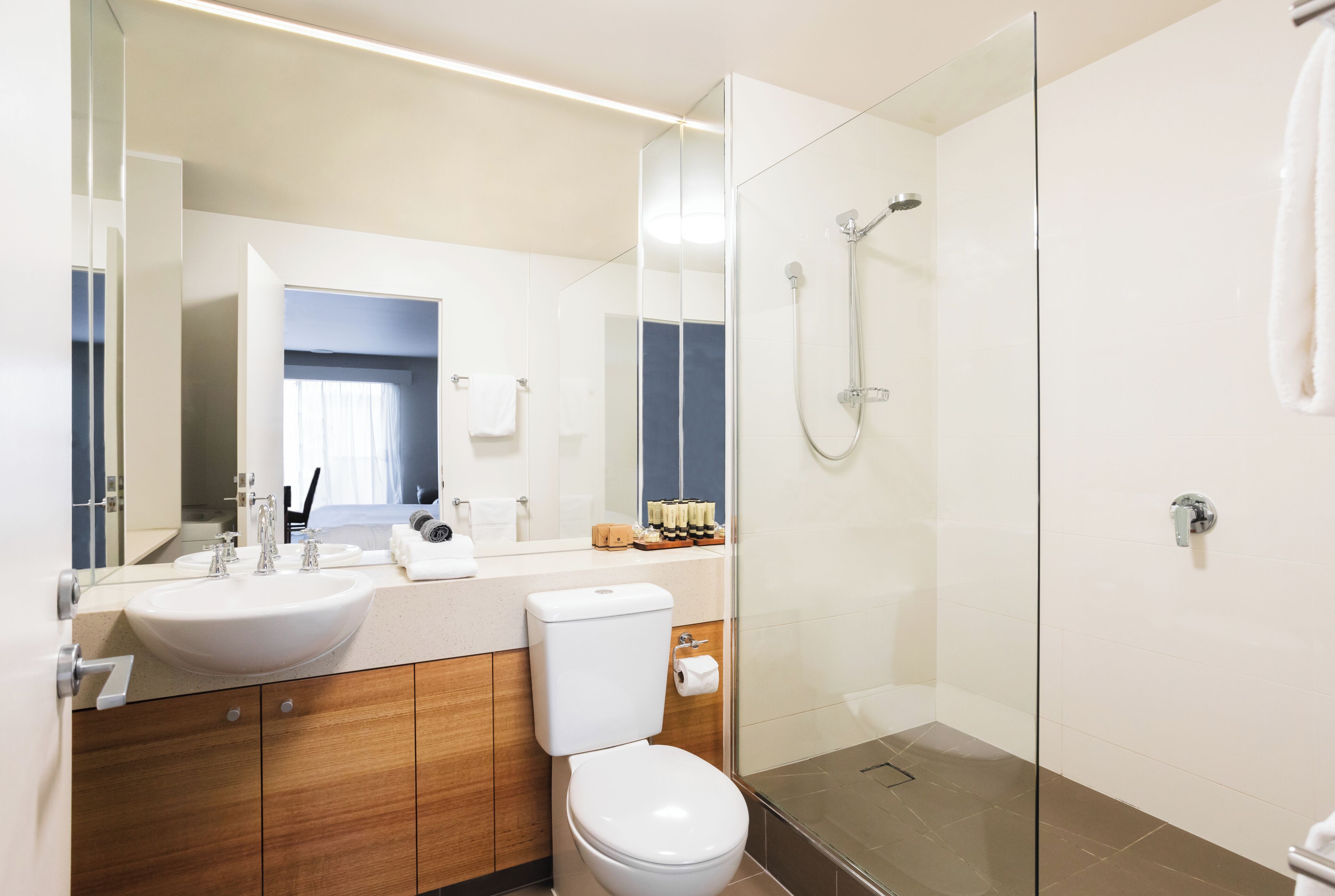 A modern bathroom with a glass-enclosed shower, a white sink, and wooden cabinetry.