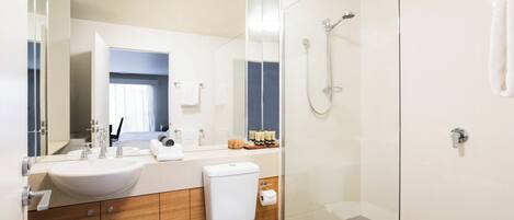 A modern bathroom with a glass-enclosed shower, a white sink, and wooden cabinetry.