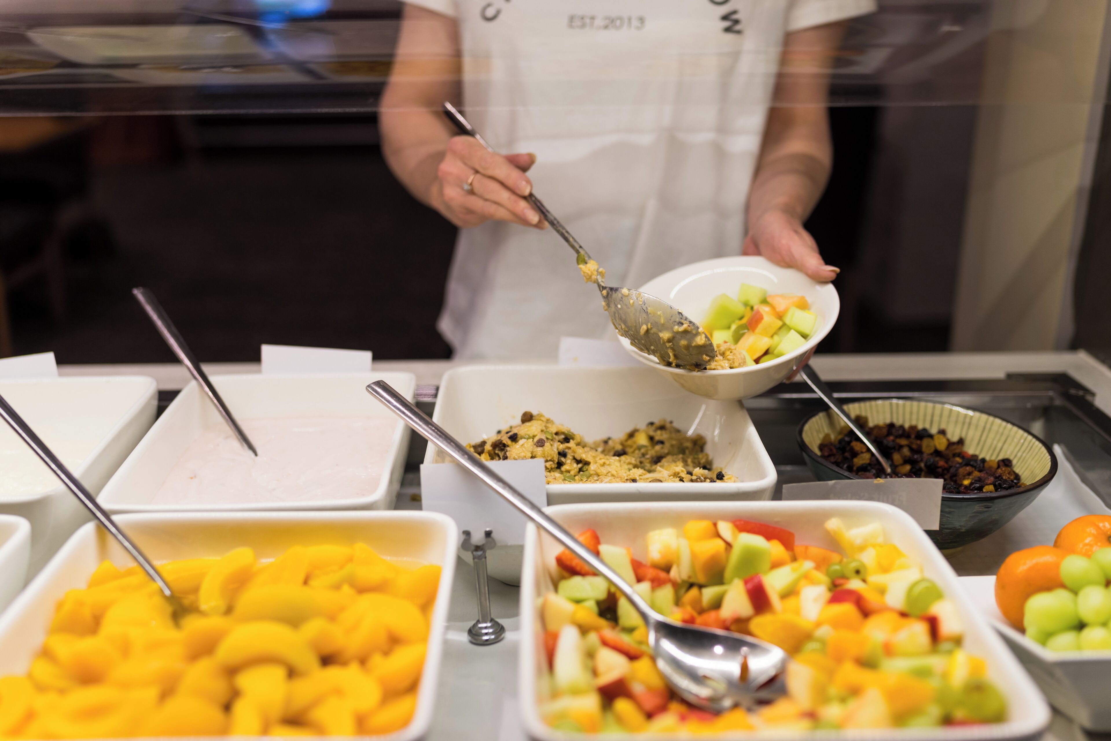 Un buffet proposant une variété de plats, notamment des fruits, et une personne qui sert les aliments.