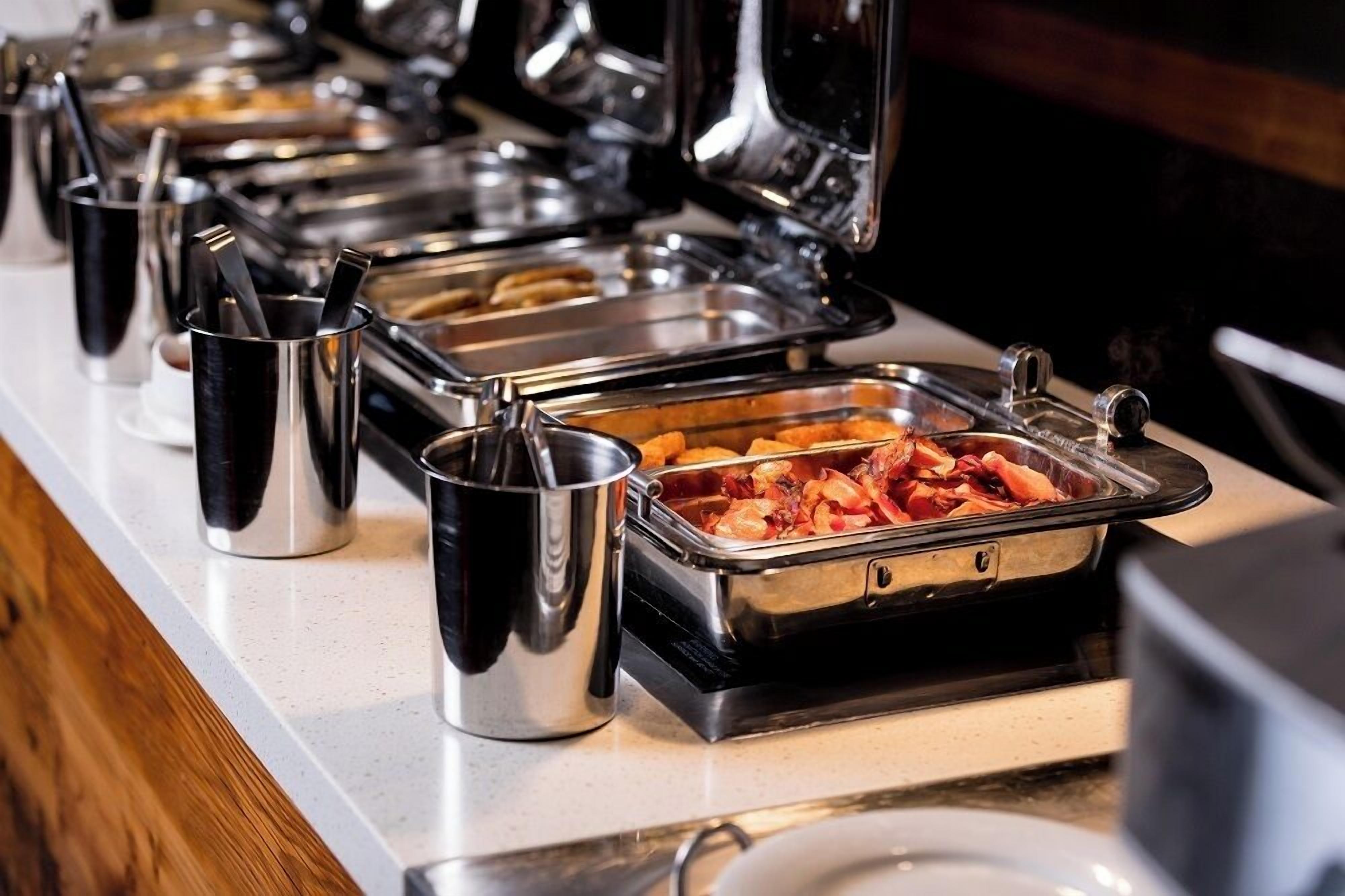 A buffet setup with various food containers and utensils.