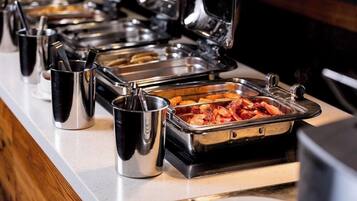 A buffet setup with various food containers and utensils.