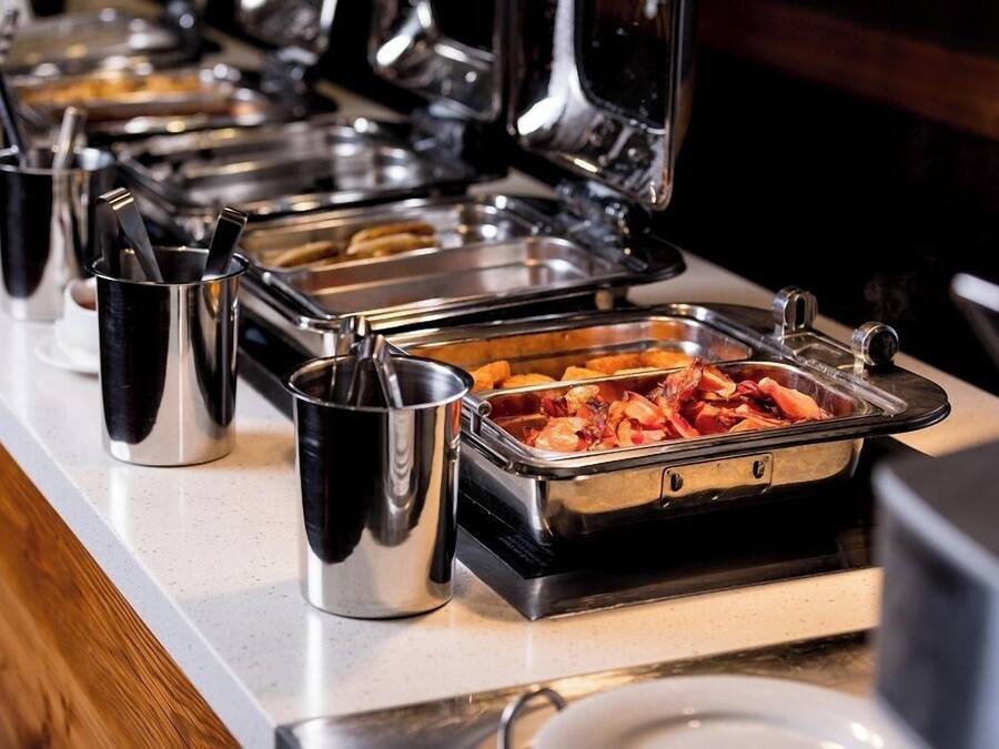 A buffet setup with various food containers and utensils.