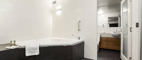 Un baño moderno con una bañera independiente, un lavamanos y un espejo.