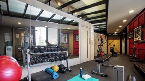 Un gimnasio con equipamiento de ejercicio, una banca y una colchoneta para yoga.