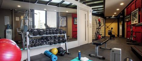 A gym with exercise equipment, a bench, and a yoga mat.