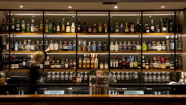 Una zona de bar con múltiples estantes llenos de botellas de licores y vasos.