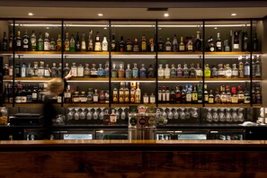 Una zona de bar con múltiples estantes llenos de botellas de licores y vasos.