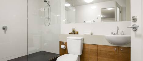 A modern bathroom with a glass-enclosed shower, a white toilet, and wooden cabinetry.