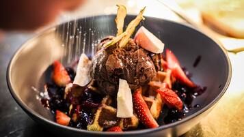 A dessert with strawberries and a chocolate sphere on a plate.