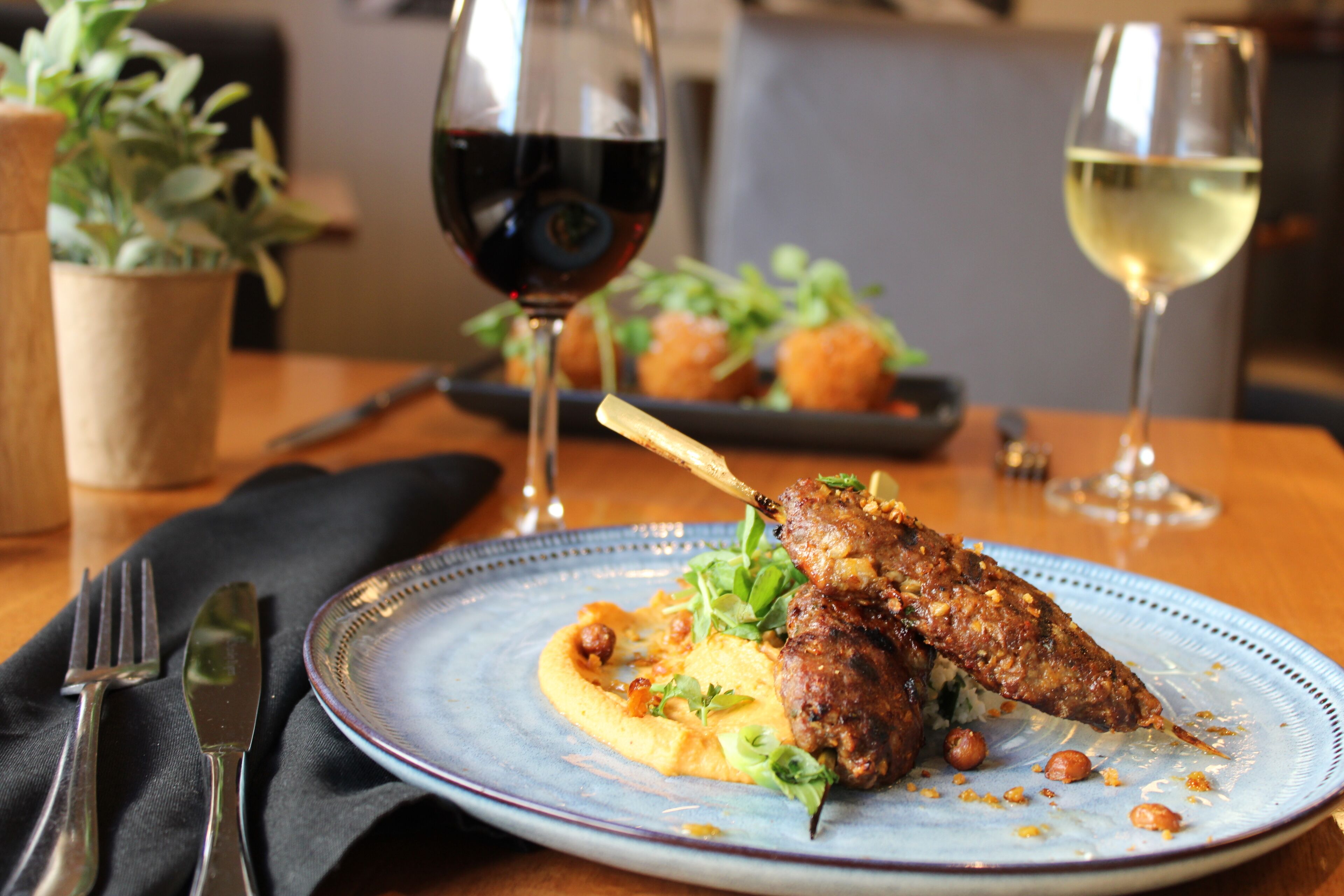 A dining table with a plate of food, a glass of red wine, and a glass of white wine.