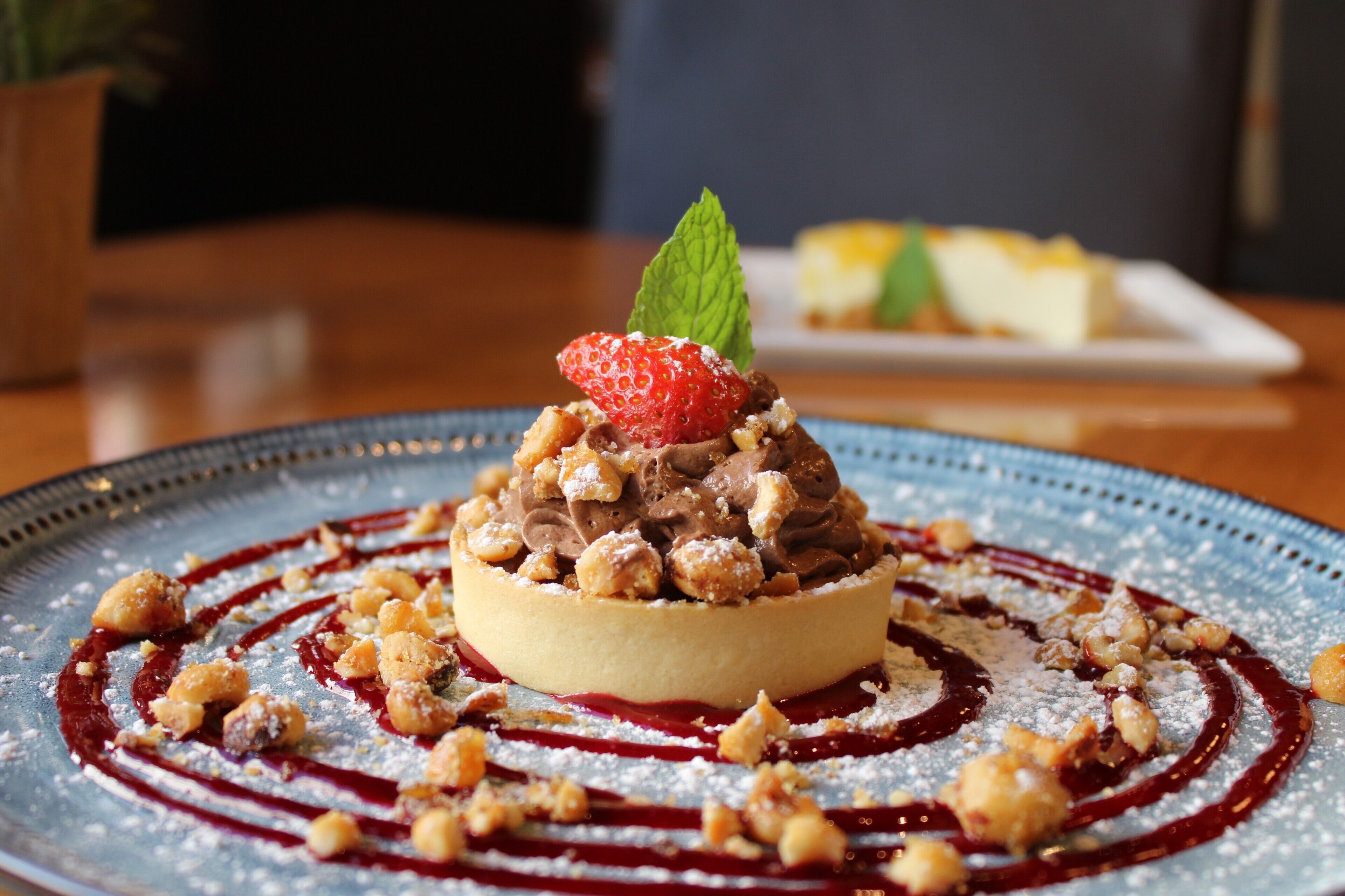A dessert on a plate with a berry sauce and powdered sugar.