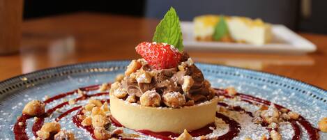 Un postre en un plato con salsa de frutos rojos y azúcar glas.