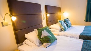 A hotel room with two beds, each with a headboard, white bedding, and a nightstand. - London Town Hotel (London)