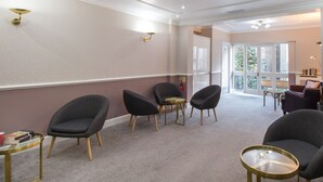 A modern waiting area with a seating arrangement, a small table, and a bookshelf. - London Town Hotel (London)