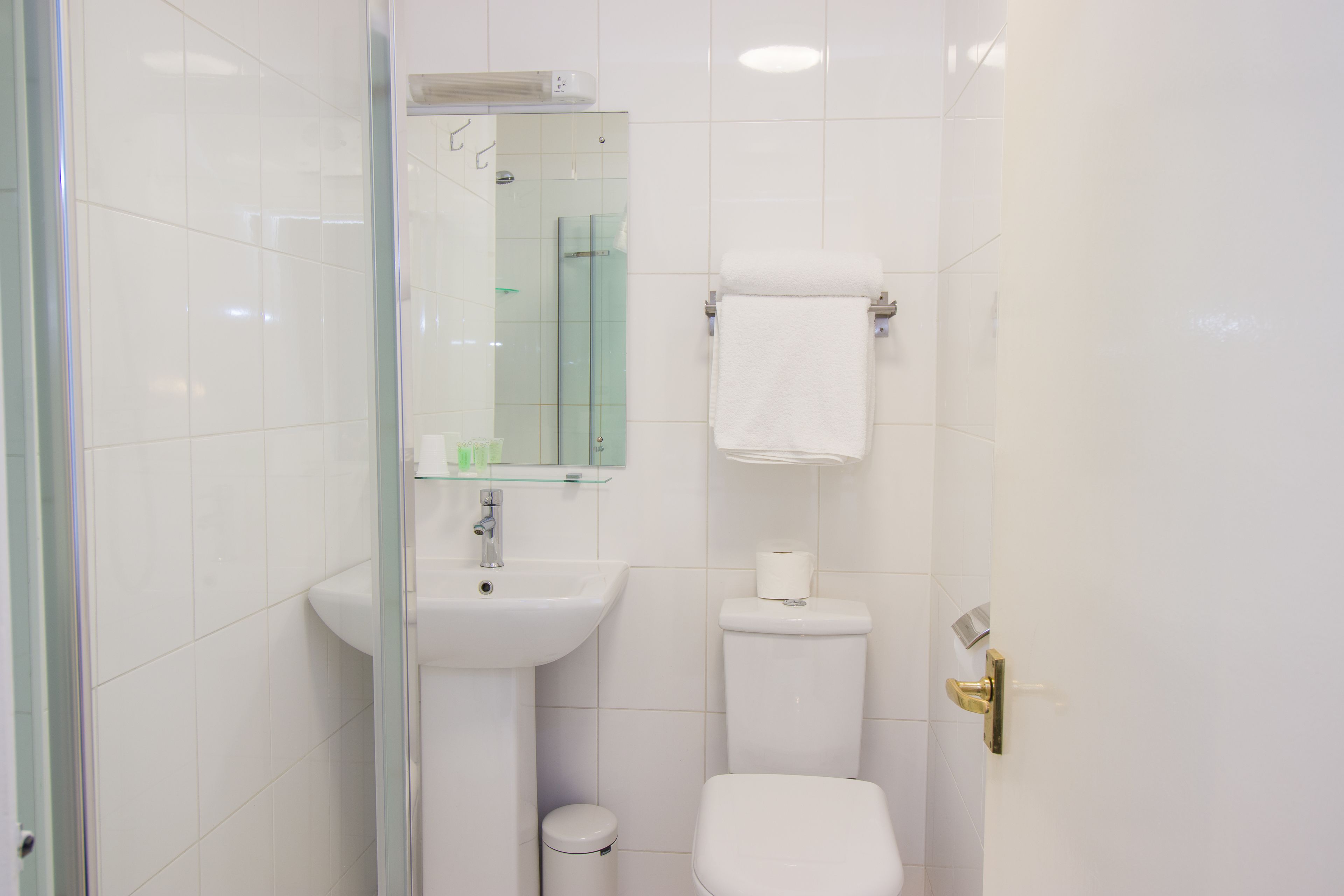 A bathroom with a glass shower enclosure, a white sink, a toilet, and a towel rack.