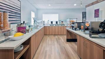 A modern kitchen with wooden cabinets, a marble countertop, and various appliances like a waffle maker and coffee machine.