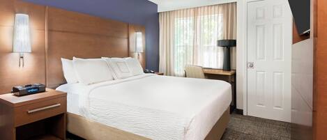 A hotel room with a large bed, bedside tables, a desk, and a TV mounted on the wall.