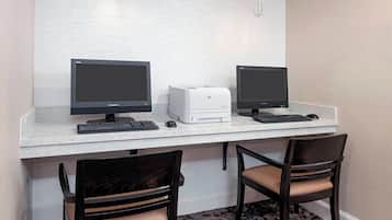 Un espacio de trabajo con dos monitores, una impresora y dos sillas.