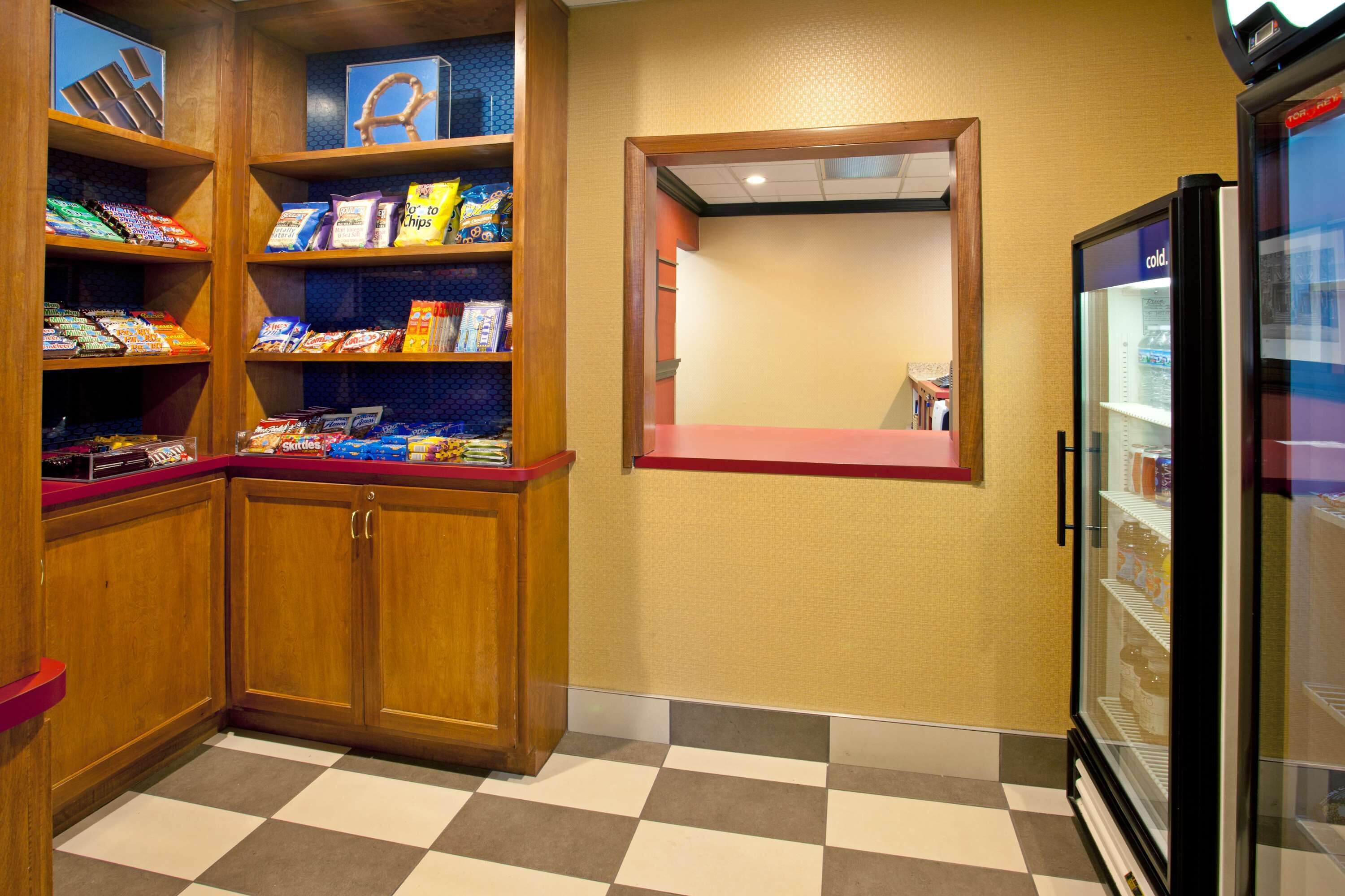 A hotel room with wooden cabinets, a checkered floor, a refrigerator, and a window with a view of the outside.