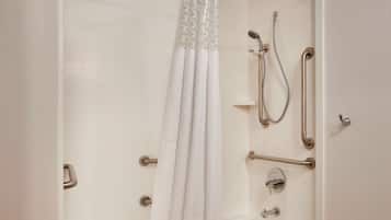 Ein modernes Badezimmer mit begehbarer Dusche, Haltegriffen und einer Duschbrause.