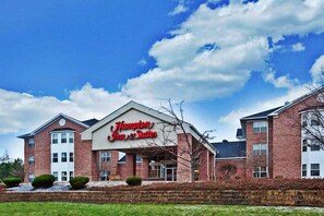Experience the sleek, modern design of this Hampton Inn & Suites, featuring a central entrance and beautifully manicured grounds.