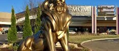 A golden lion statue in a landscaped area with a building in the background.