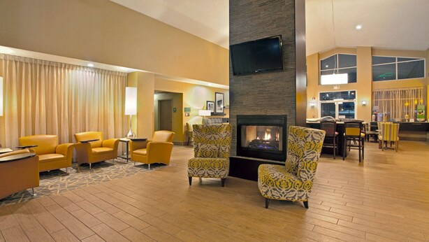A spacious lobby with a fireplace, yellow armchairs, and a seating area with patterned chairs. - Hampton Inn & Suites Cleveland/Independence (Independence)