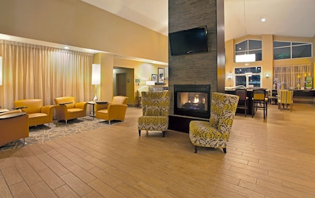 A spacious lobby with a fireplace, yellow armchairs, and a seating area with patterned chairs.