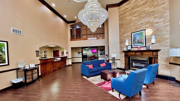A hotel lobby with a reception desk, blue sofas, a fireplace, and a chandelier. - Comfort Suites Georgetown (Georgetown)