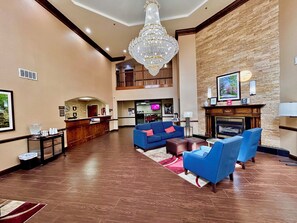 A hotel lobby with a reception desk, blue sofas, a fireplace, and a chandelier. - Comfort Suites Georgetown (Georgetown)