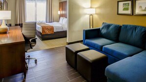 A hotel room with a bed, a desk, a blue sofa, and a small table. - Comfort Suites Georgetown (Georgetown)