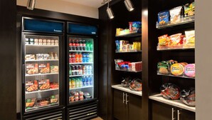 A refrigerated display case with various frozen food items and a shelf stocked with snacks and packaged goods.