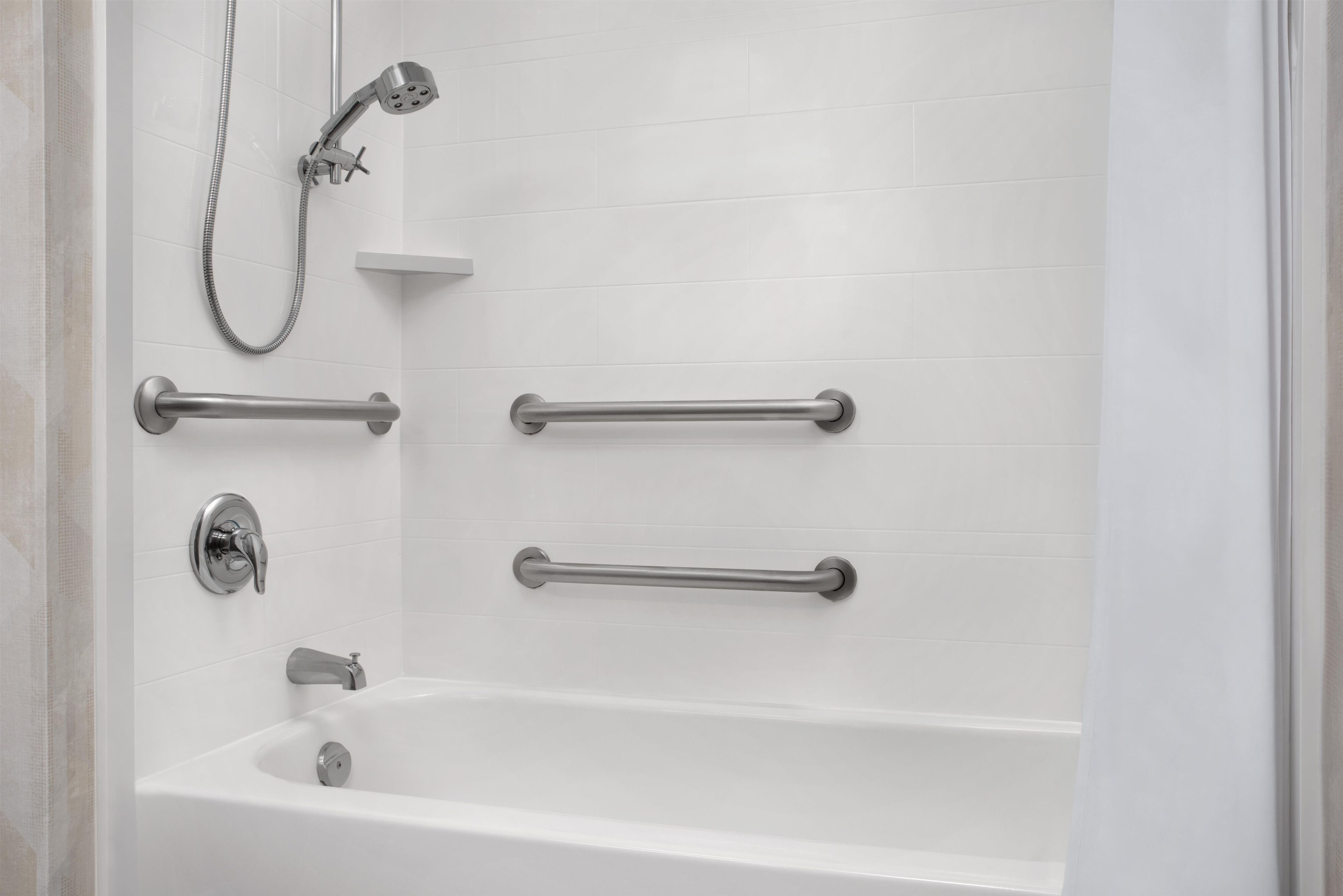 Un baño moderno con bañera, barras de apoyo y cabezal de ducha.