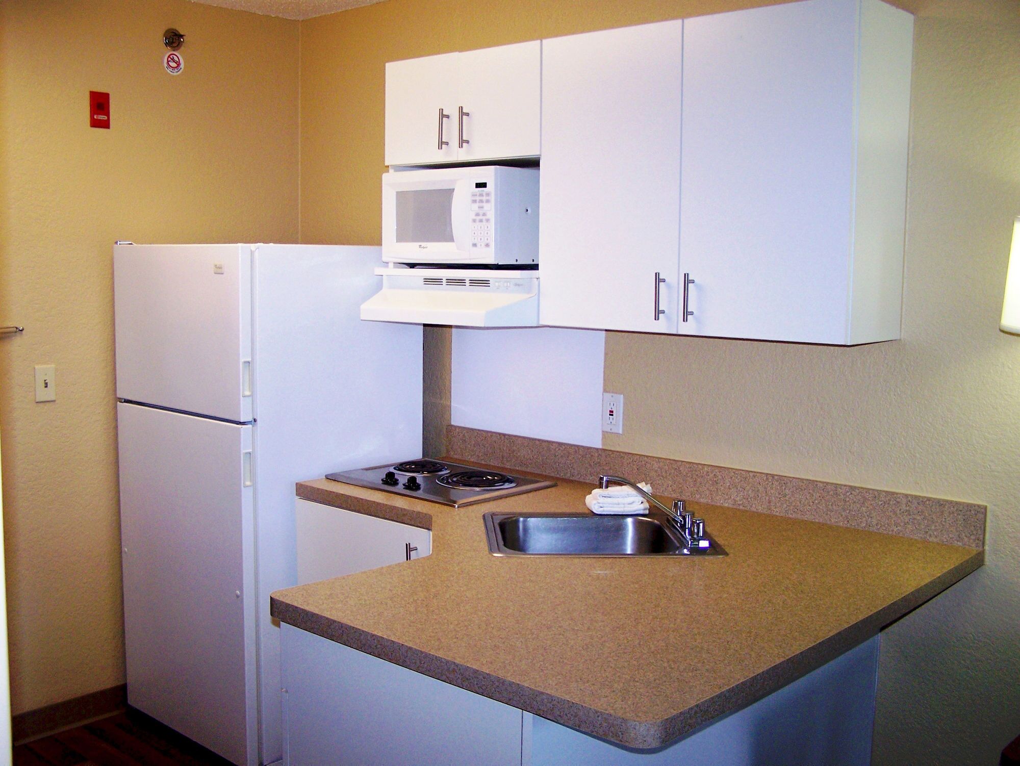 Una cocina compacta equipada con refrigerador, microondas, estufa y pileta.