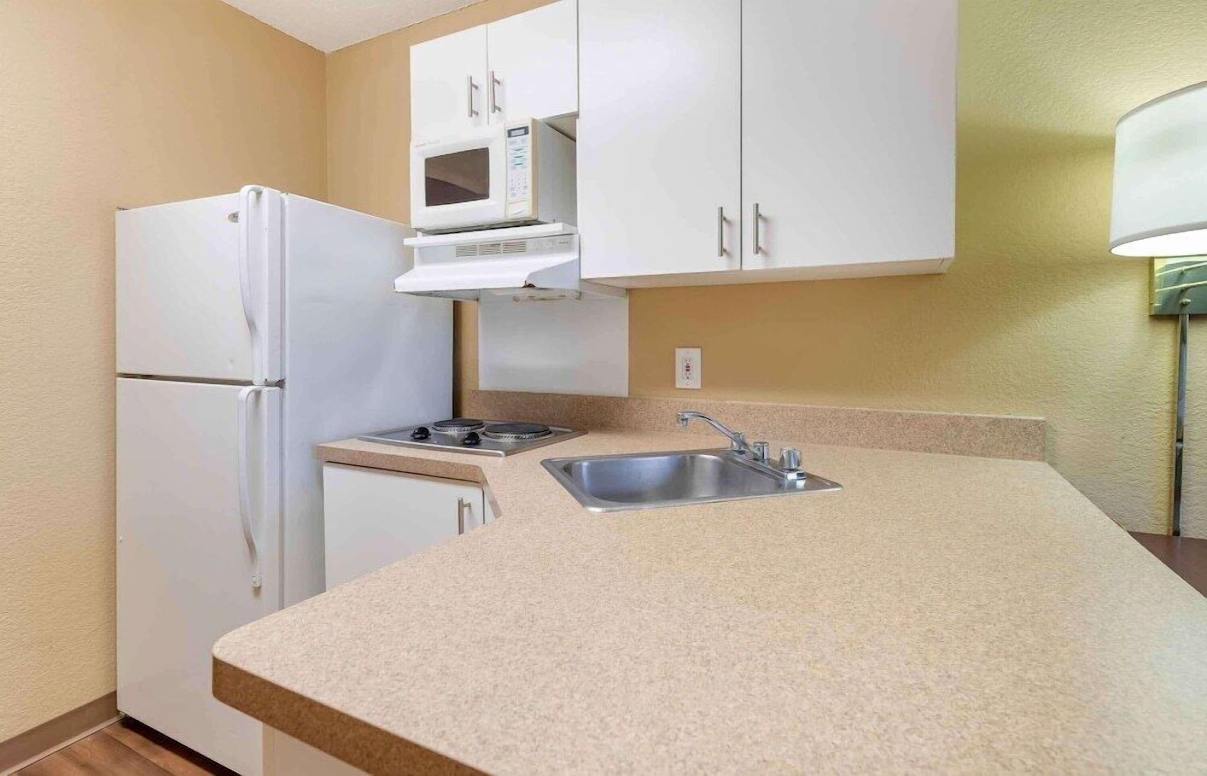 A compact kitchen with a refrigerator, microwave, stove, and sink.