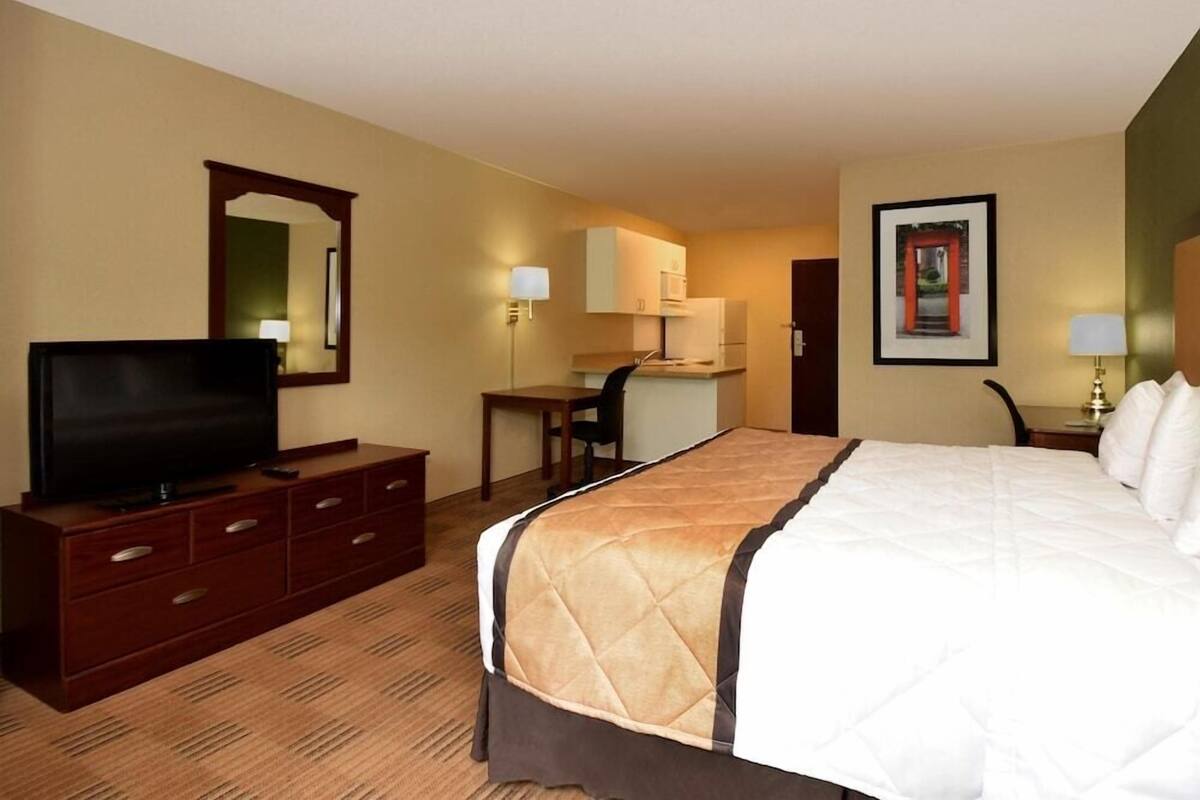 Una habitación de hotel con cama, televisión, escritorio y silla.