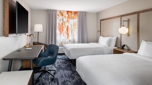 A hotel room with two beds, a desk, a chair, a TV, and a window with curtains.
