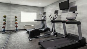 A modern gym with treadmills, elliptical machines, and free weights.