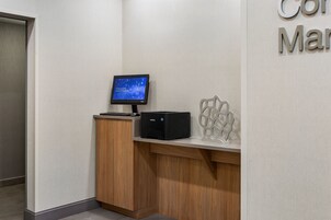 Una recepción con un monitor, una impresora y un elemento decorativo en la pared.