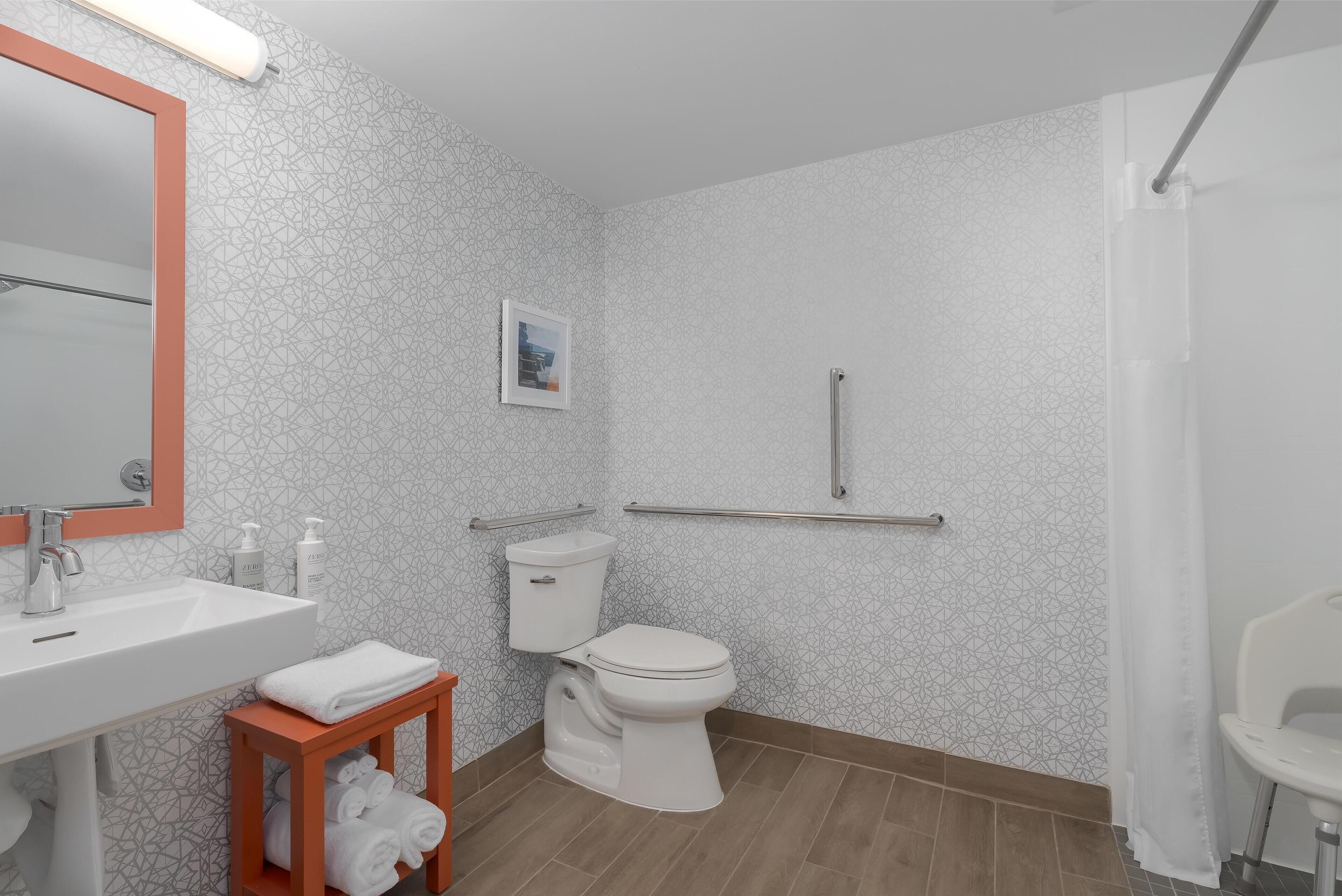 Een badkamer met een wit wastafelmeubel, toilet en douchehoek.