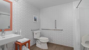 Een badkamer met een wit wastafelmeubel, toilet en douchehoek.