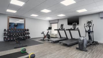 A gym with treadmills, an elliptical, a stationary bike, and a variety of dumbbells.