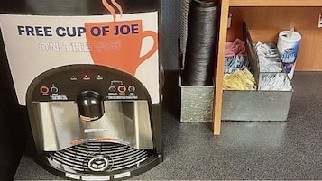 A coffee machine with a sign offering a free cup of joe on the go.