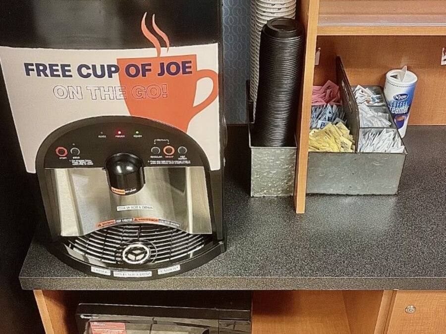 A coffee machine with a sign offering a free cup of joe on the go.