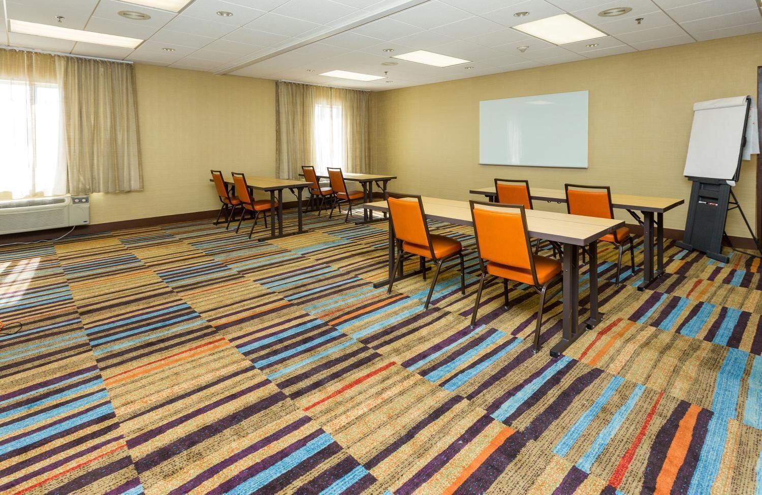 A conference room with a patterned carpet, multiple tables, and chairs.