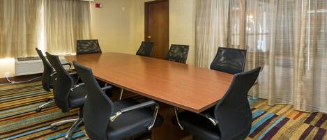 A conference room with a long table, six chairs, and a patterned carpet.
