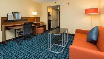 Habitación de hotel con escritorio, silla y sofá naranja.