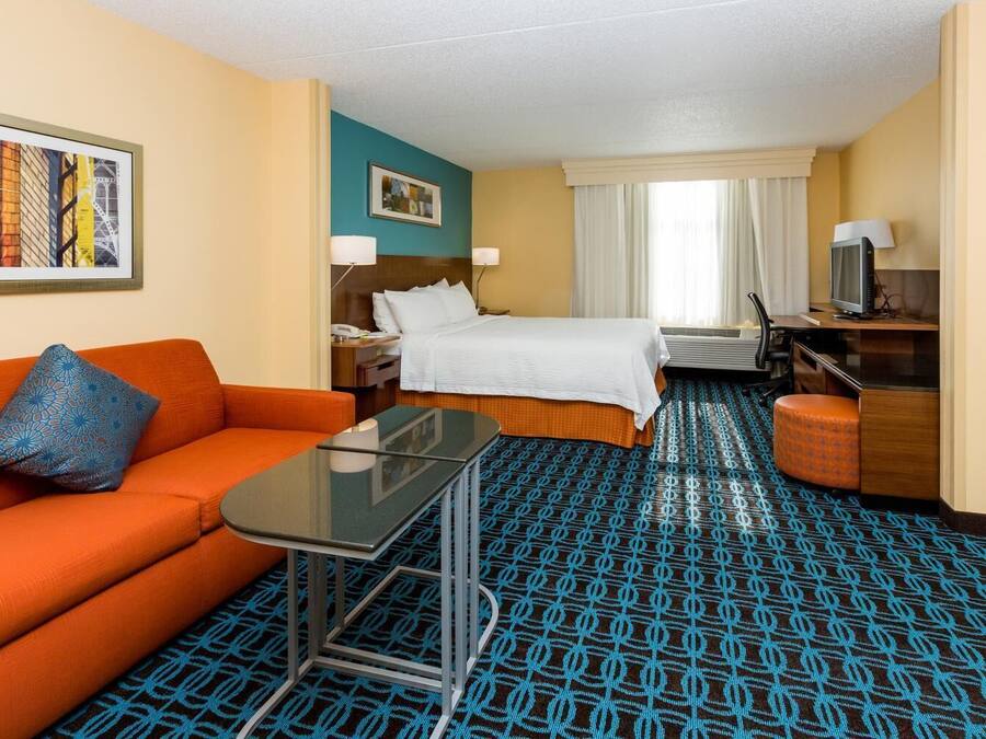 A hotel room with a bed, a desk, a chair, a sofa, and a small table.