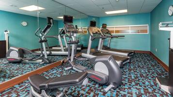 Un gimnasio con cintas de correr, elípticas y una bicicleta estática.